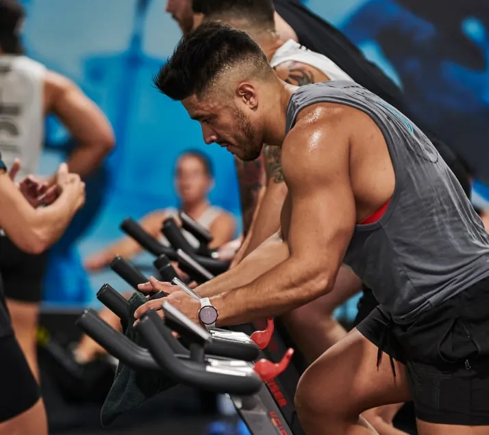 A member driving hard on the spin bike during a cardio block